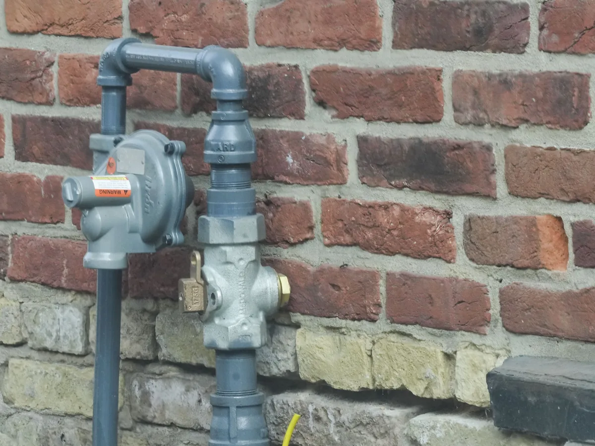 Gas meter and regulator mounted on the outside wall of a house