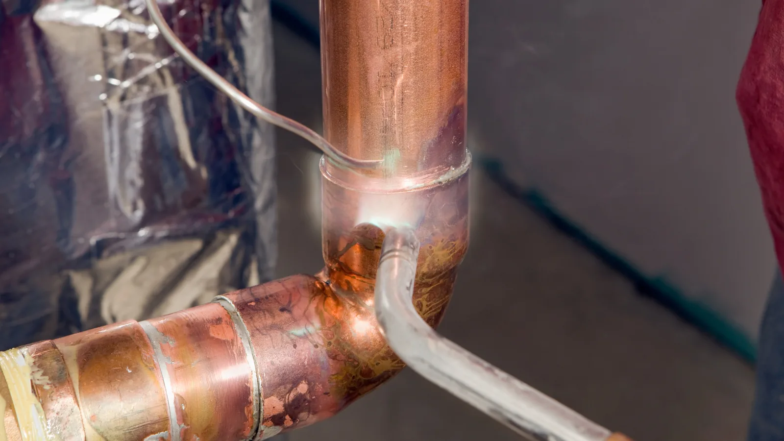 Freshly soldered copper water line joints at a tee and elbow