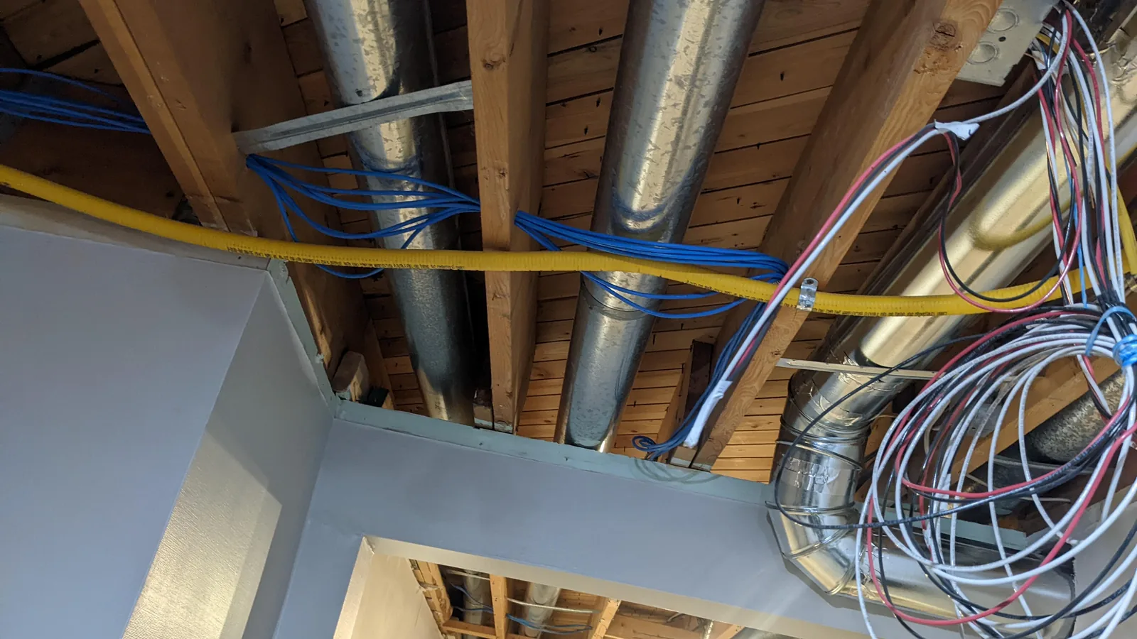 Gas and water lines run together across a basement ceiling