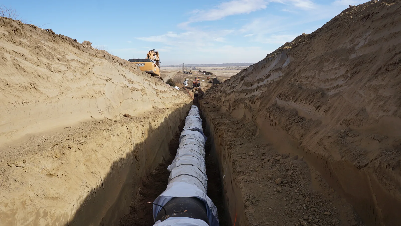 Long open pipe trench cut across dry high-desert ground