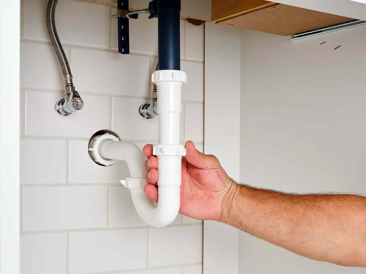 Hand fitting the P-trap back together under a sink