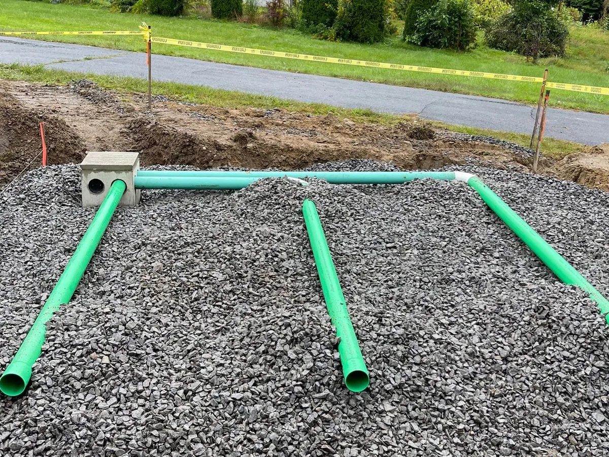 Perforated drainfield pipe laid across a gravel leach field bed