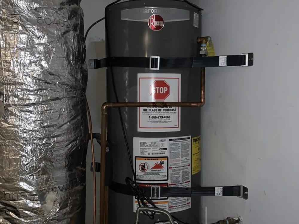 Tank water heater strapped to the wall with new copper water connections