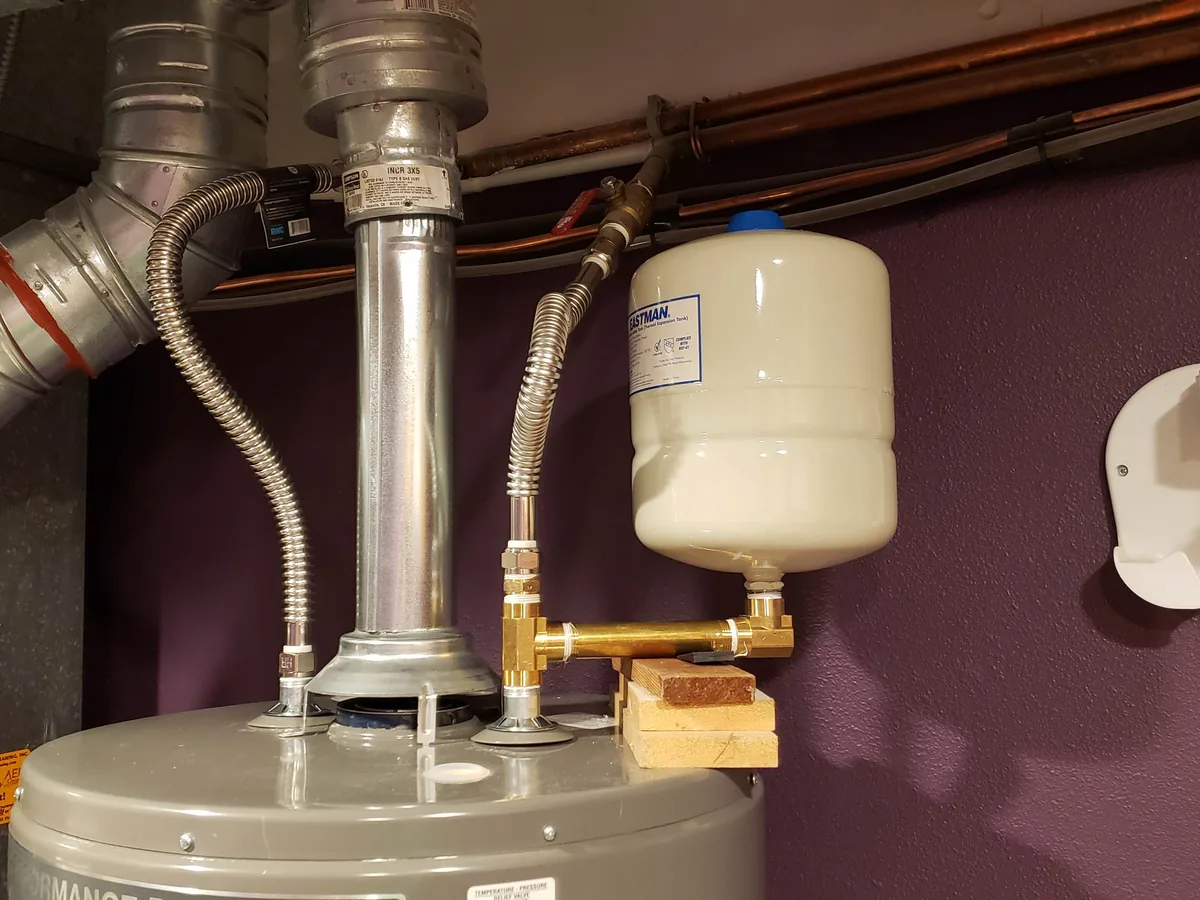 Top of a newly installed gas water heater with flue vent, flex connector and expansion tank